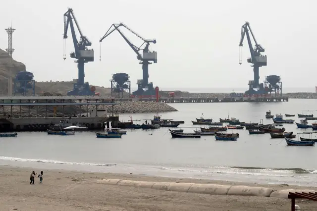 Pequeños barcos pesqueros amarrados en la playa de Chancay, con el gran puerto en construcción al fondo. 