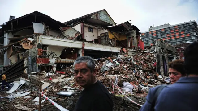 Las personas observan edificios de escombros en concepción, afectados por el terremoto chileno de 2010.