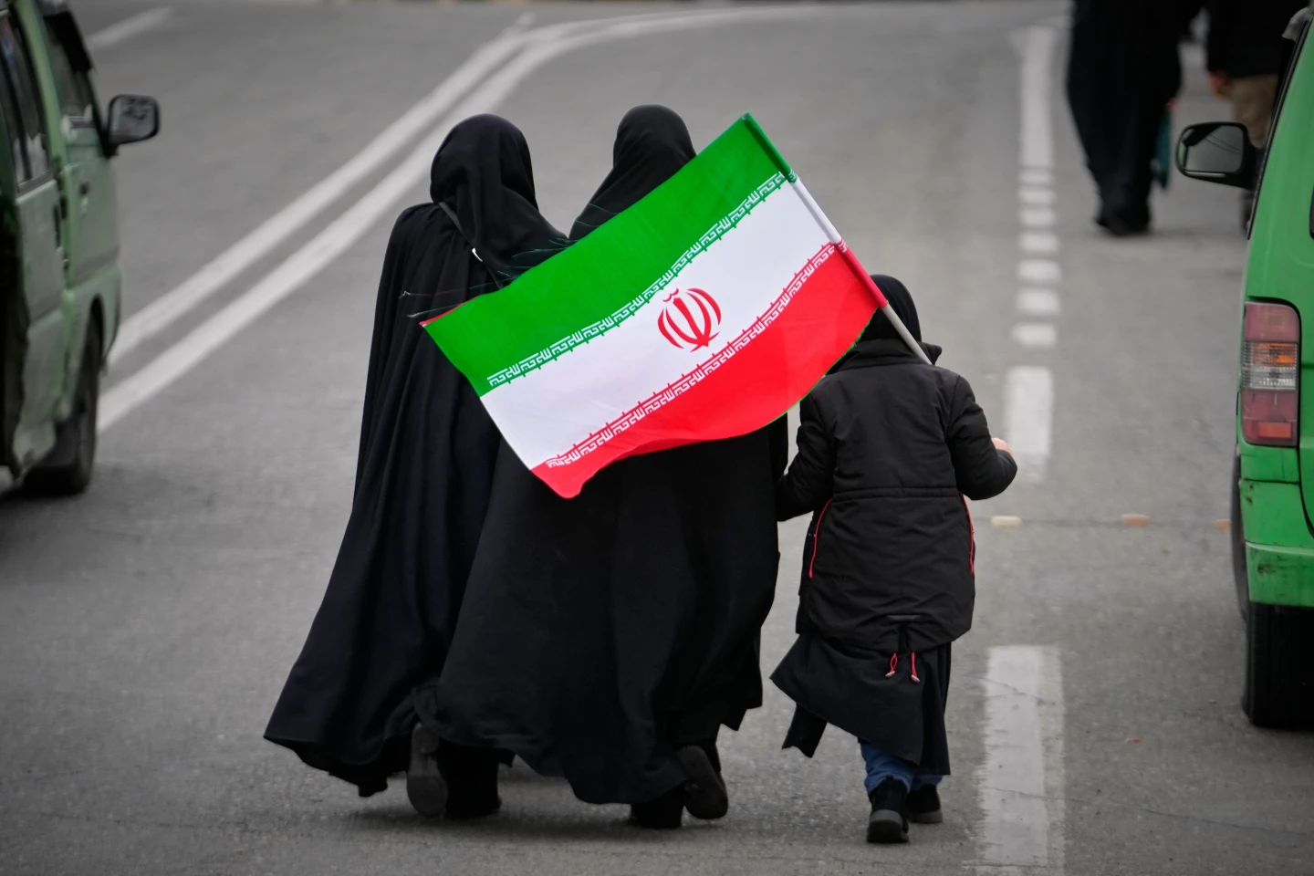 Dos mujeres y un menor con una bandera iraní