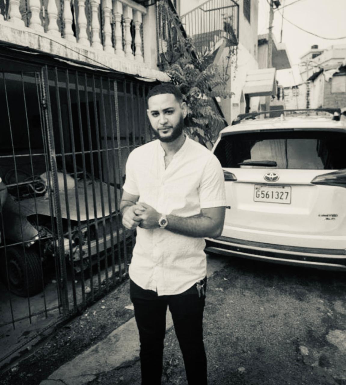 Hombre parado junto al coche estacionado.