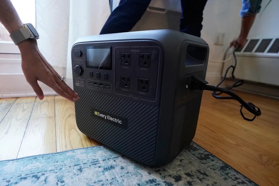 Sonam Velani y Yan Sim conectan una batería Every Electric para alimentar su aire acondicionado como parte de un programa piloto con la empresa eléctrica de la ciudad Con Edison para reducir la presión en la red eléctrica, el lunes 27 de abril de 2026, en el distrito de Brooklyn de Nueva York. (Foto AP/Alyssa Goodman)