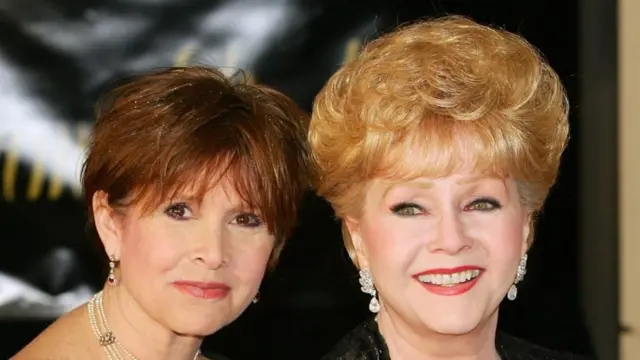 Carrie Fisher y Debbie Reynolds miran sonriendo a la cámara.