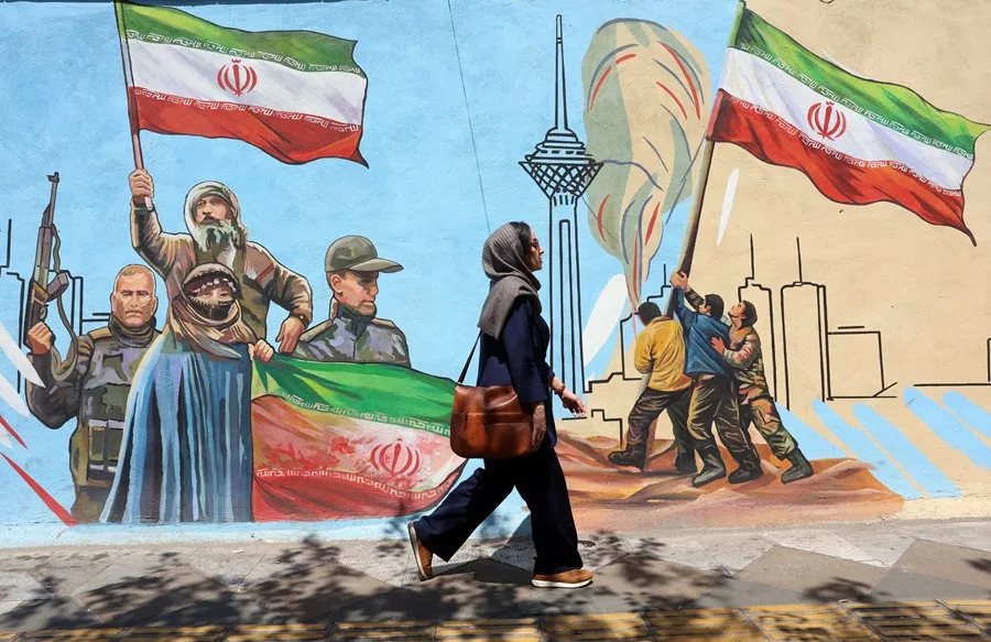 Una mujer camina frente a un mural en Teherán, en una imagen de archivo. EFE/EPA/ABEDIN TAHERKENAREH