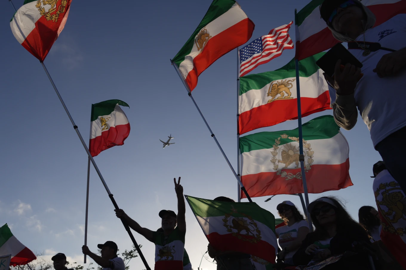 Varias personas ondean banderas iraníes prerrevolucionarias durante una protesta frente al estadio de Los Ángeles.
