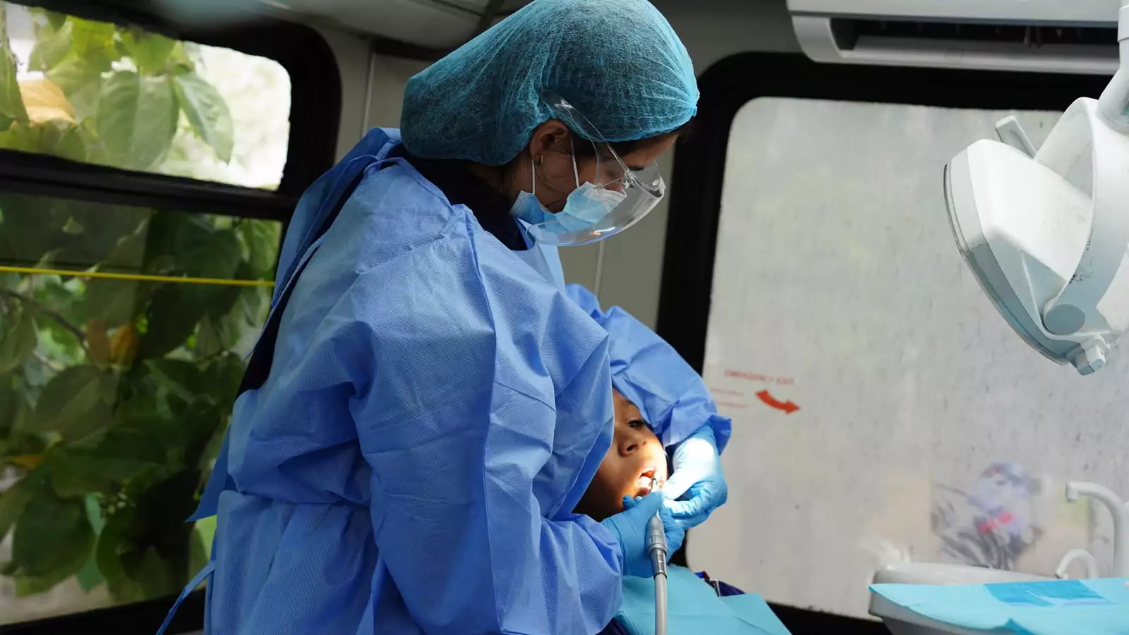 Personal de salud atiende a un niño durante un procedimiento odontológico en una unidad móvil
