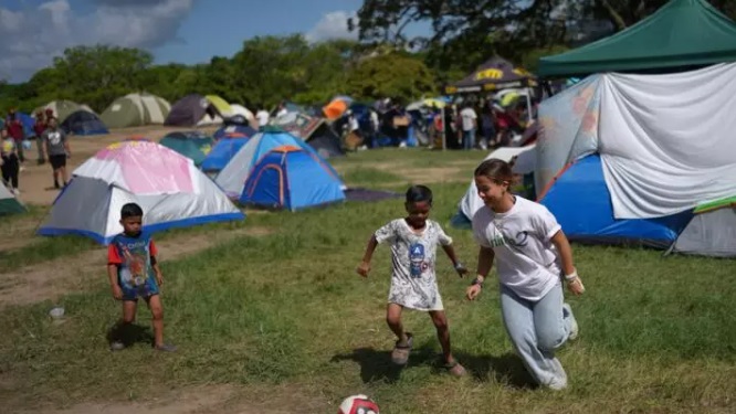 Un voluntario juega fútbol con niños en el Parque Generalísimo Francisco de Miranda, donde acampan las personas cuyas casas fueron dañadas por los terremotos, el miércoles 1 de julio de 2026. © AP/Matias Delacroix