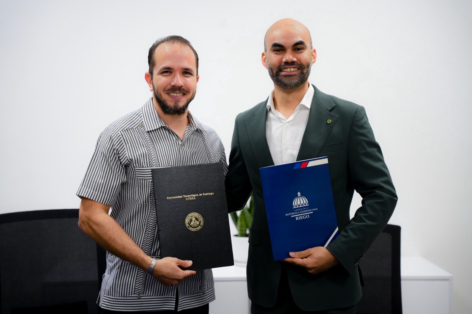 Claudio Caamaño Vélez y Luis BIenvenido Gómez muestran los convenios firmados entre TNR y UTESA