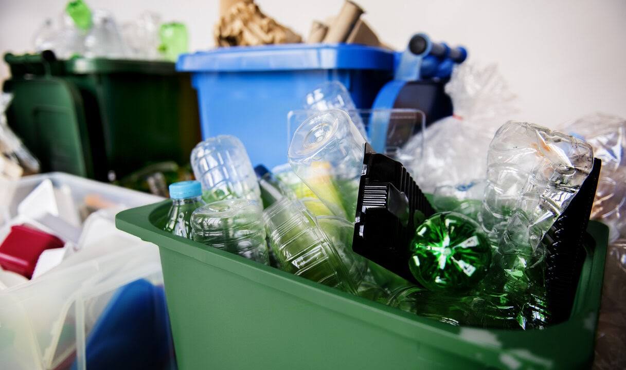 Contenedores de reciclaje con botellas de plástico y otros residuos en una escena de gestión de residuos