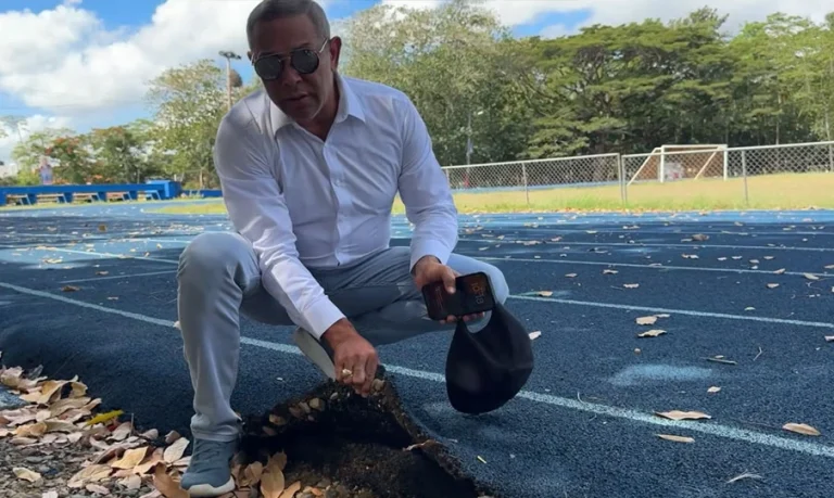 Un hombre señala una sección elevada de una pista de atletismo en una instalación deportiva al aire libre