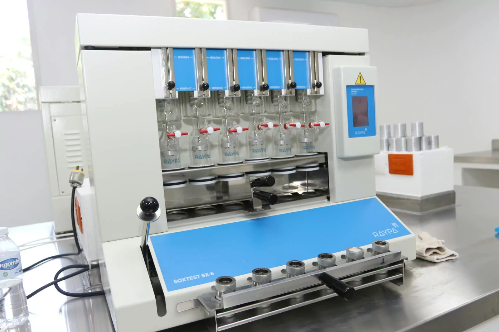 Equipo de laboratorio para análisis químicos sobre una mesa de acero, en el contexto de noticias científicas o de salud.