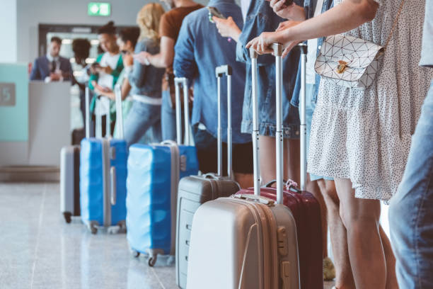 La gente lleva maletas de viaje en un aeropuerto. Foto de referencia