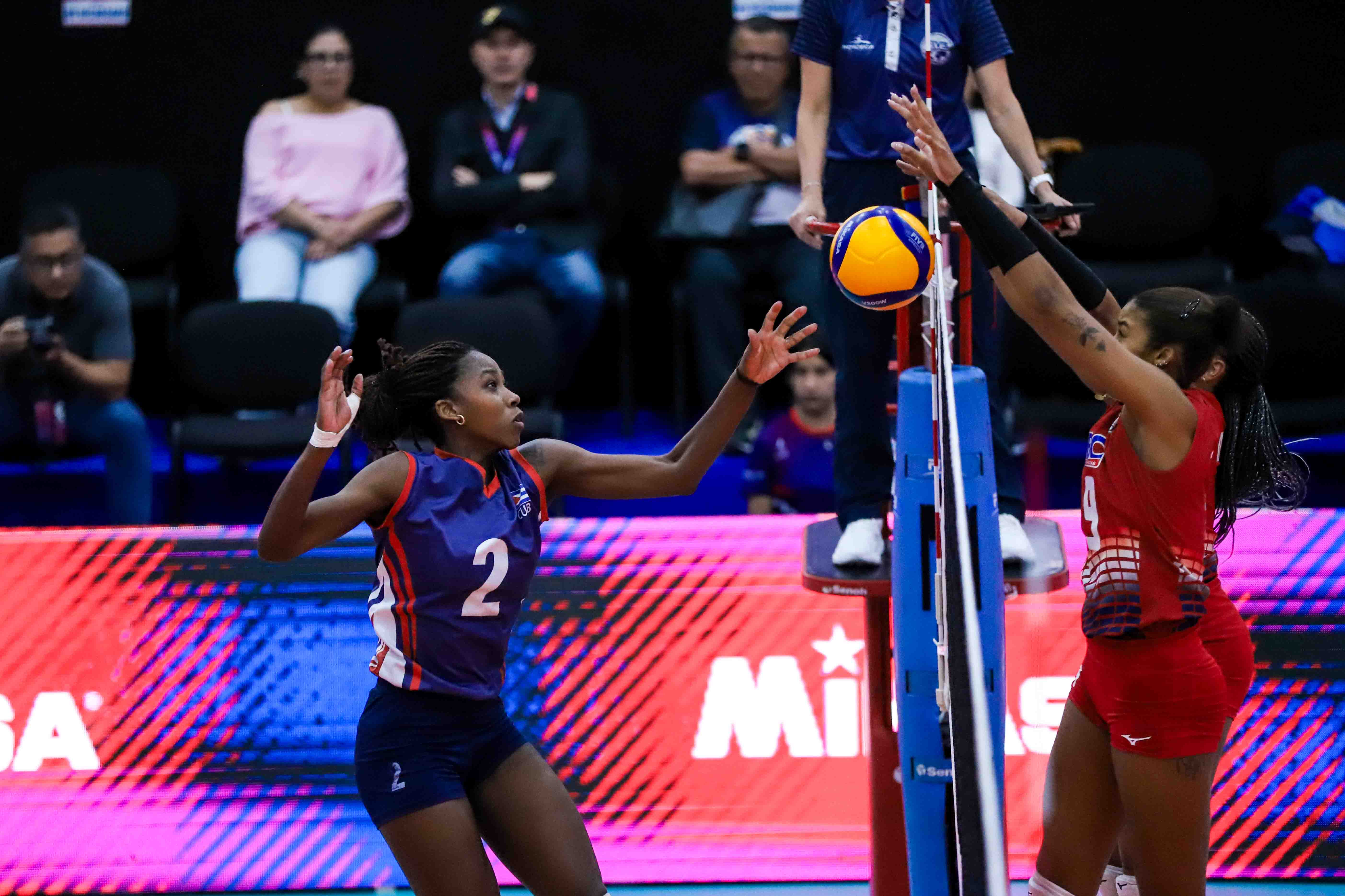 Martínez, de Cuba, intenta burlar la defensa de dos jugadores de República Dominicana en el segundo set.