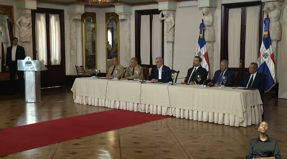 Funcionarios y comandantes militares en una mesa de reunión oficial con banderas de República Dominicana