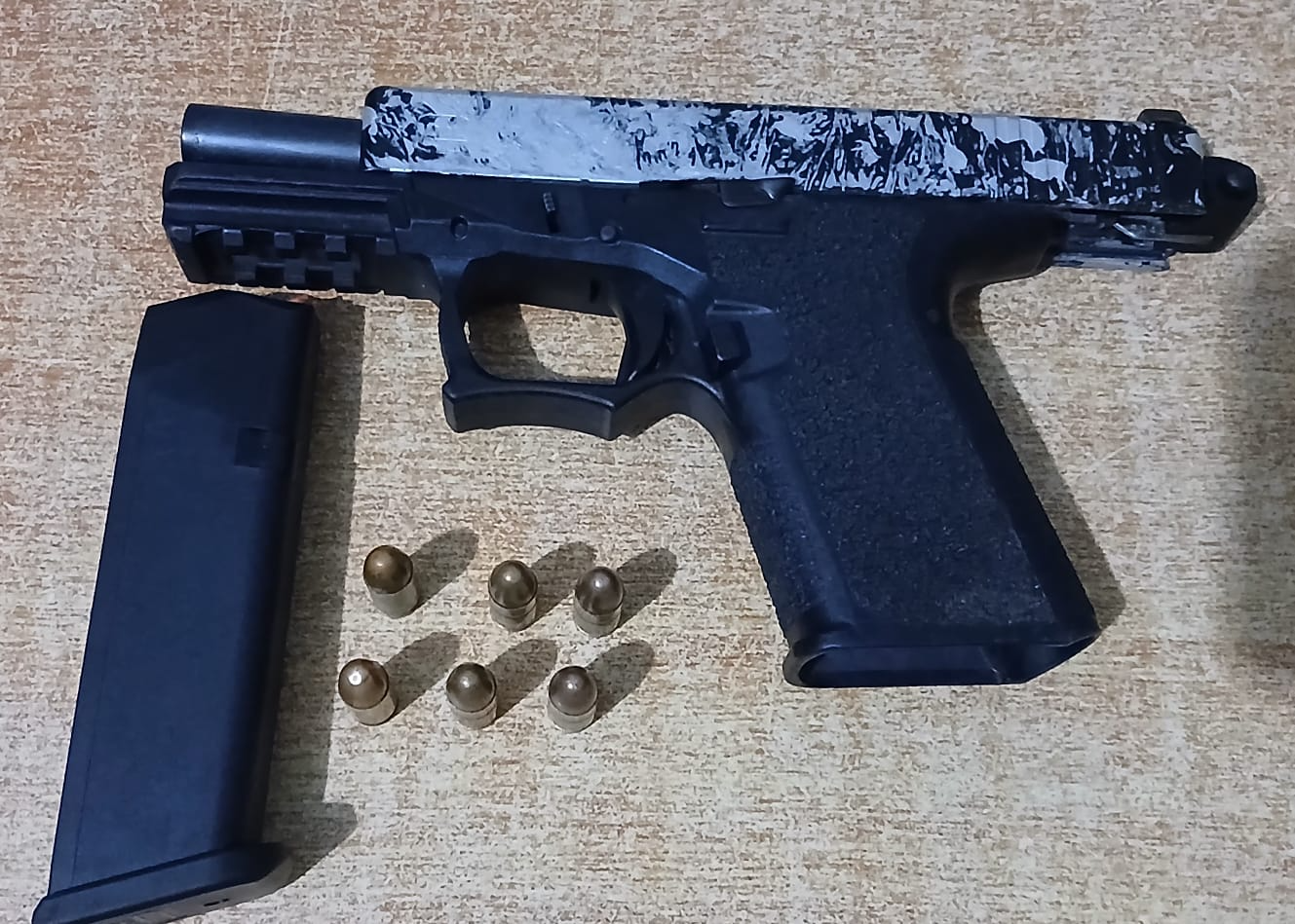 Pistola negra con cargador separado y seis municiones sobre una superficie, en el contexto de una noticia policial en República Dominicana.