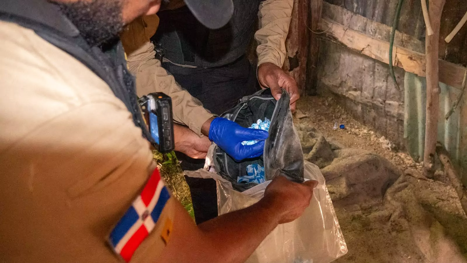 Agentes inspeccionan una mochila con fundas azules durante un operativo en una vivienda de República Dominicana