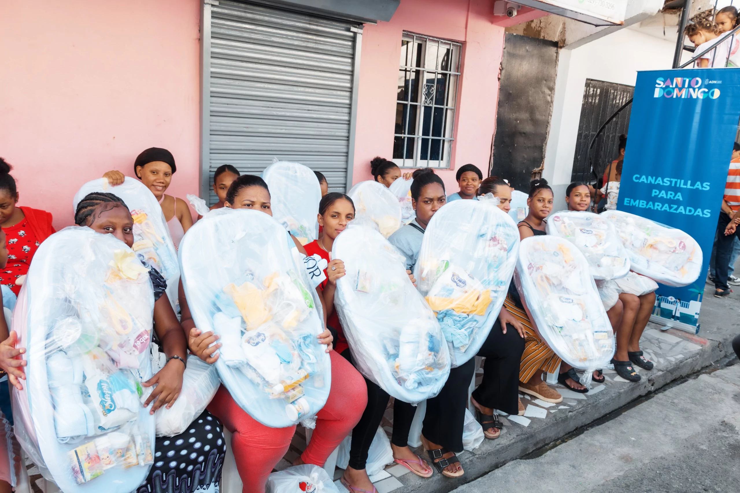 Mujeres sostienen canastas para embarazadas durante operativo social de ADN en Villas Agrícolas, Distrito Nacional