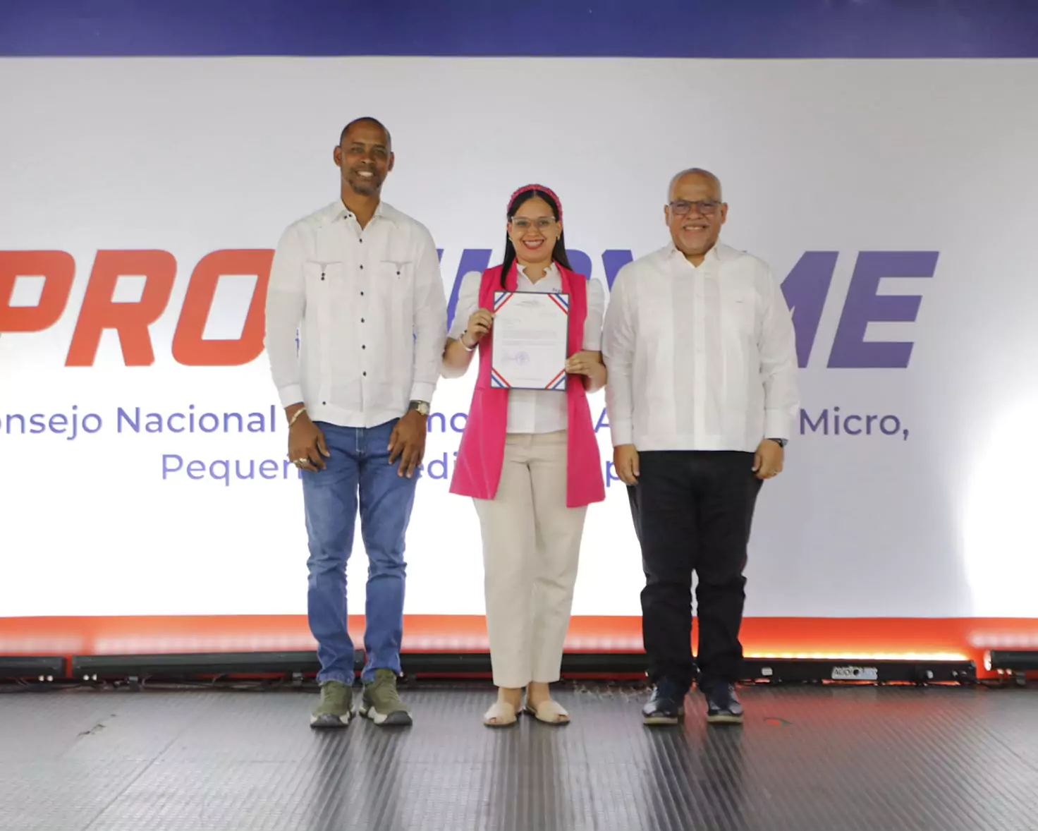 Mujer sostiene certificado en evento de Promipyme en La Romana, donde se otorgaron créditos a microempresarios.