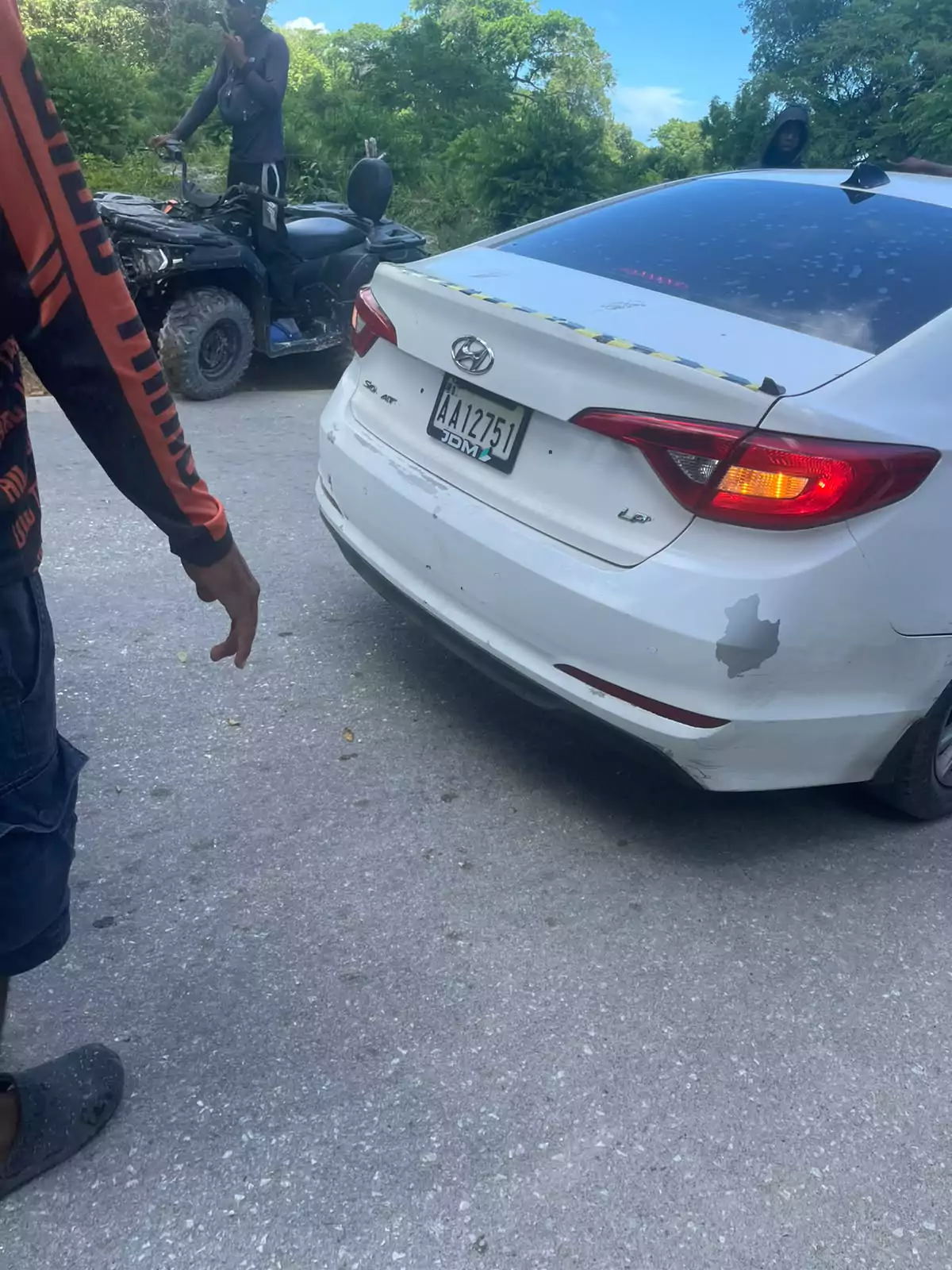 Parte trasera de un coche blanco junto a un buggy en Punta Cana; Familiares muestran la matrícula tras accidente con dos heridos