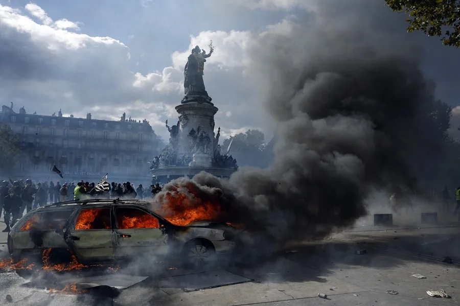 Un automóvil arde en la Place de la République mientras estallan enfrentamientos entre manifestantes y la policía durante una protesta contra el aumento del costo de vida y los recortes en París, Francia. EFE/YOAN VALAT