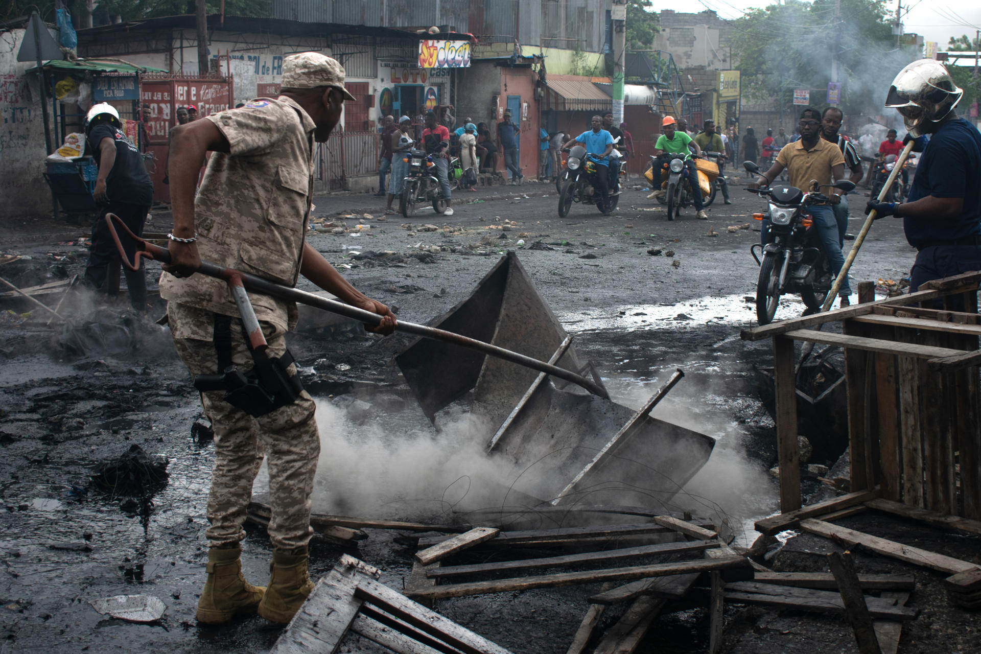 Un miembro de la Unidad Departamental para el Mantenimiento del Orden (UDMO) de Haití retira una barricada durante una protesta este martes, en Puerto Príncipe (Haití). Familias desplazadas por la violencia de bandas armadas haitianas se manifestaron para exigir ayuda económica y garantías de seguridad que les permitan regresar a sus barrios de origen. EFE/ Jonet St. Élois