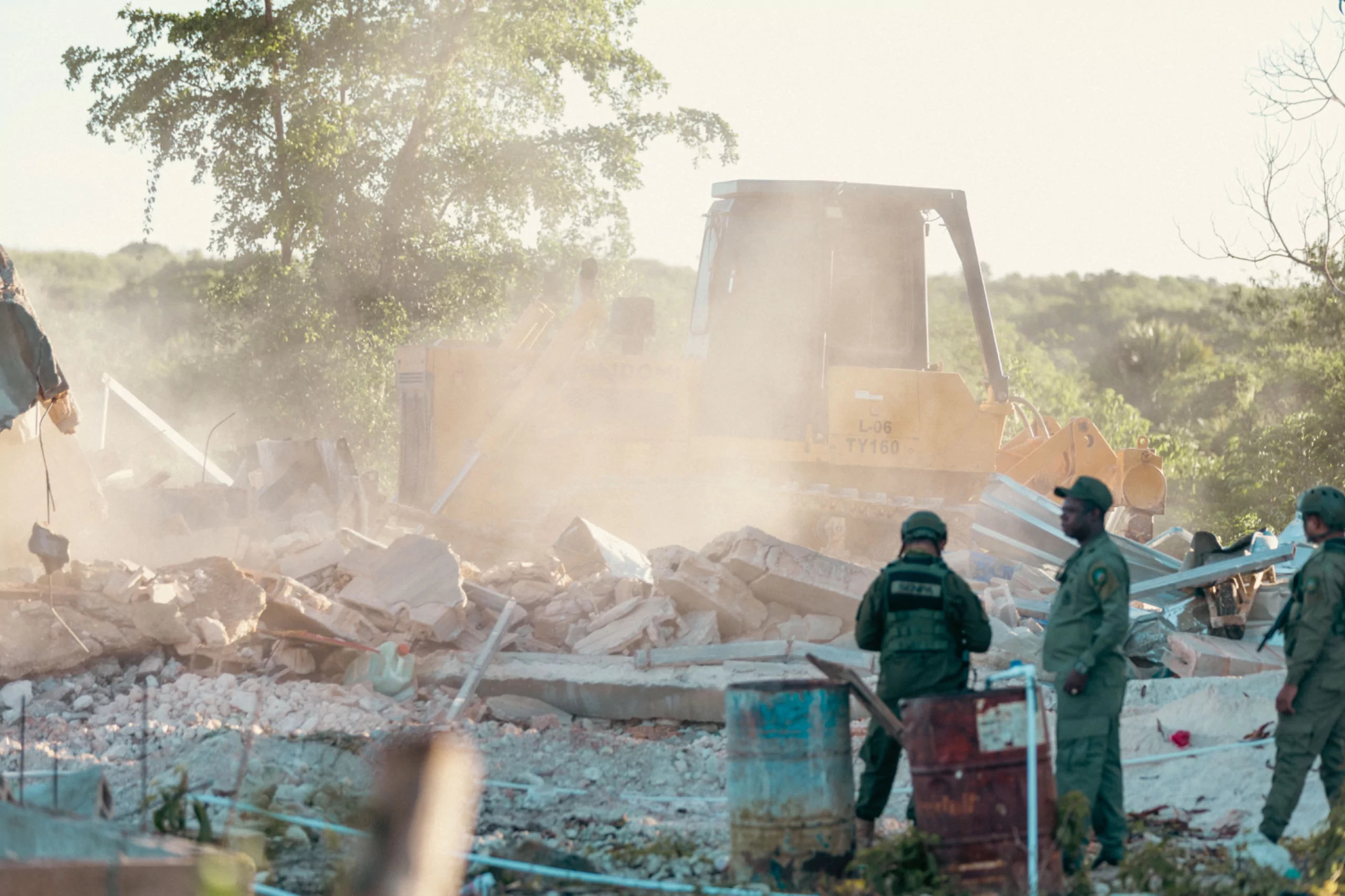 Bulldozer retira escombros mientras agentes monitorean un operativo contra estructuras ilegales en Hoyo Claro, La Altagracia.