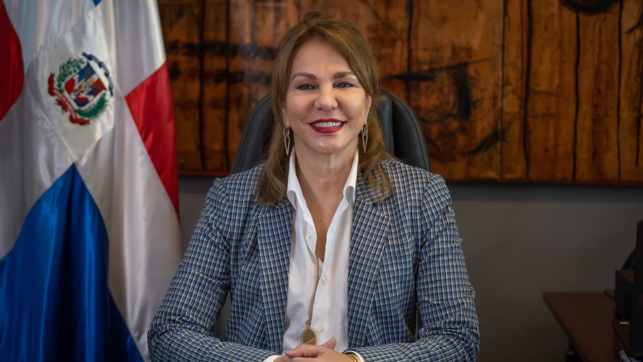 Funcionario posa en el despacho junto a la bandera dominicana, en el marco de la auditoría de la Cámara de Cuentas al DICOM
