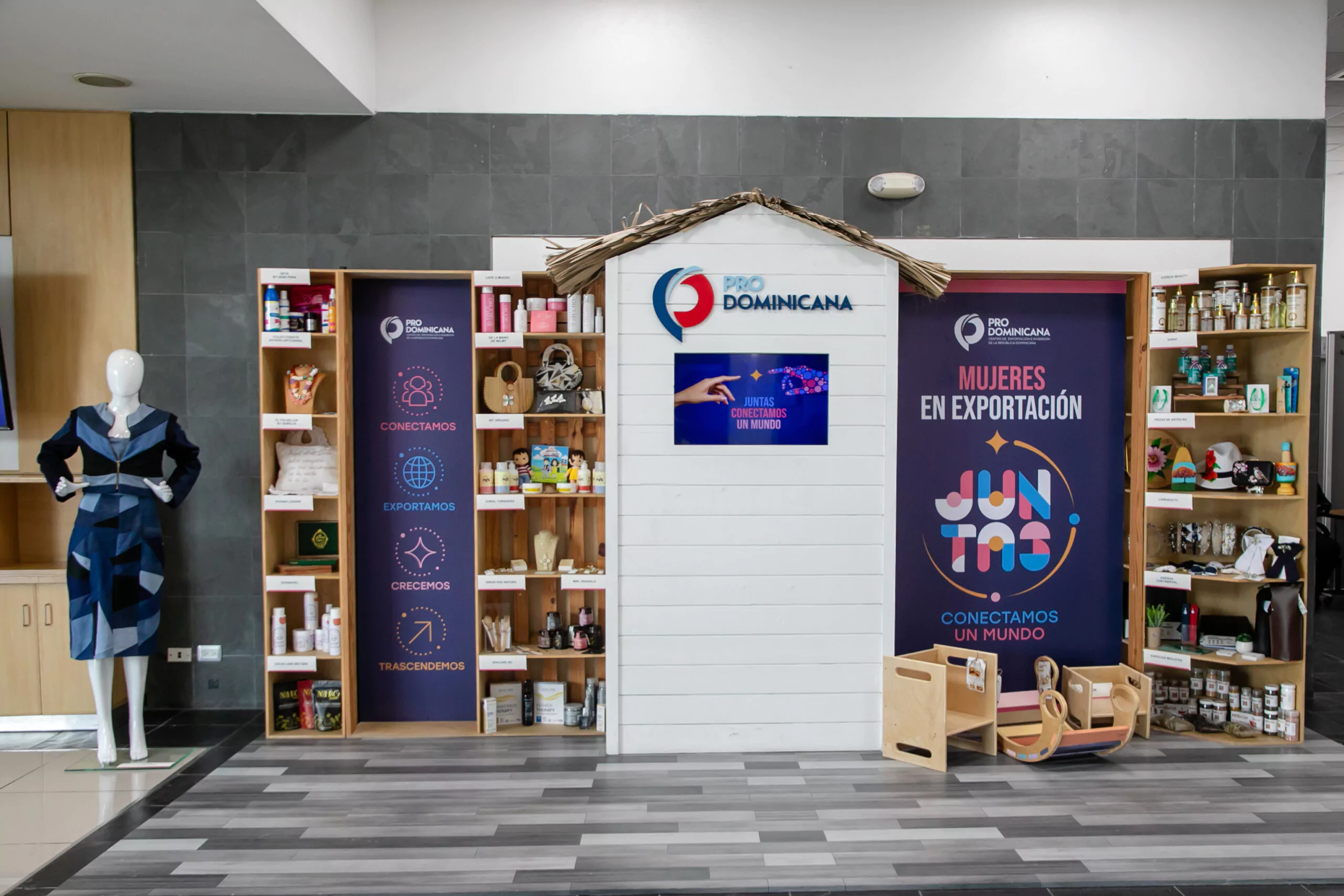 Exposición ProDominicana sobre la mujer en la exportación, con productos locales y un maniquí en un espacio promocional