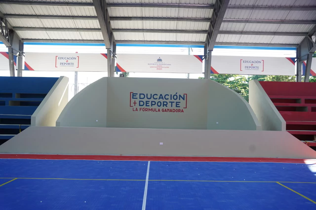Cancha cubierta con gradas y cartel de 'Educación + Deportes' en una instalación deportiva en República Dominicana