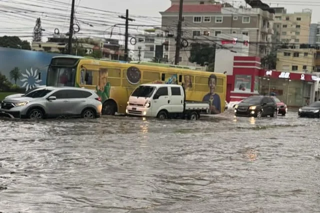 Vehículos y autobuses circulan por calles inundadas por fuertes lluvias en República Dominicana bajo alerta verde