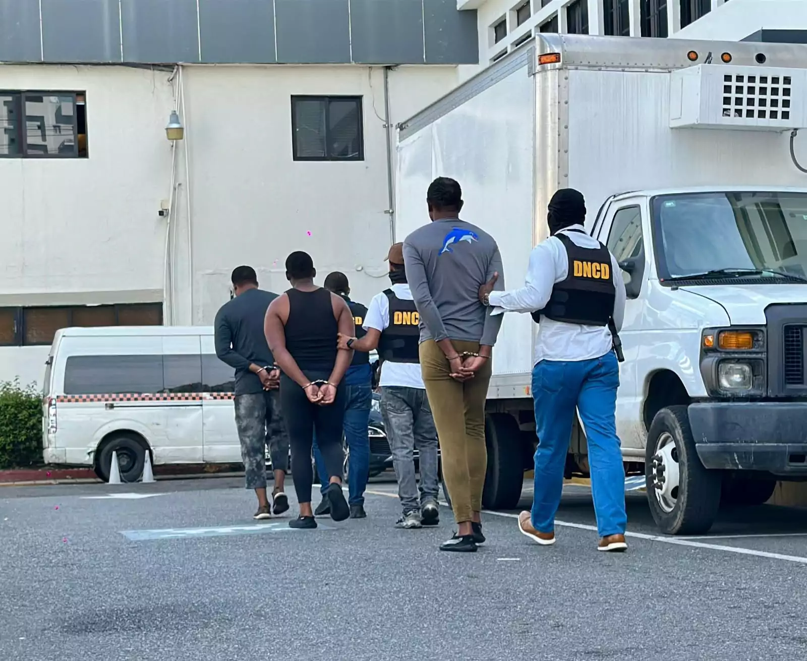 Agentes de la DNCD trasladan a varios detenidos tras operativo de incautación de 555 paquetes de presunta cocaína en Baní