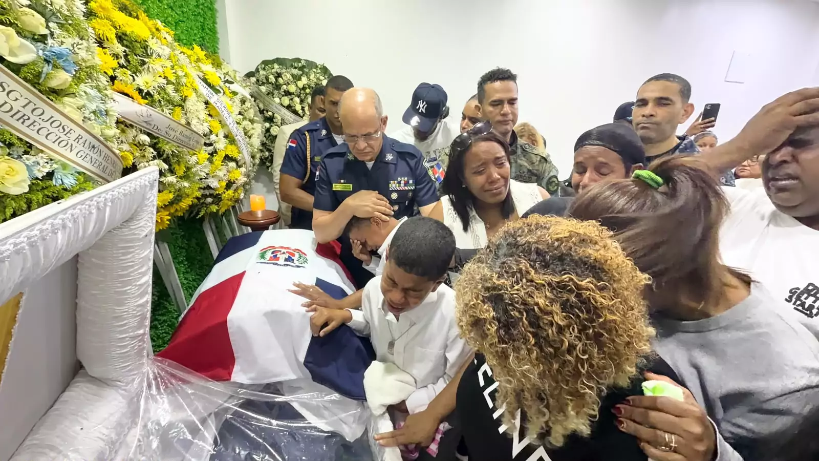 Familiares lloran junto al ataúd cubierto con la bandera dominicana en el velorio del sargento José Ramón Henríquez Mejía