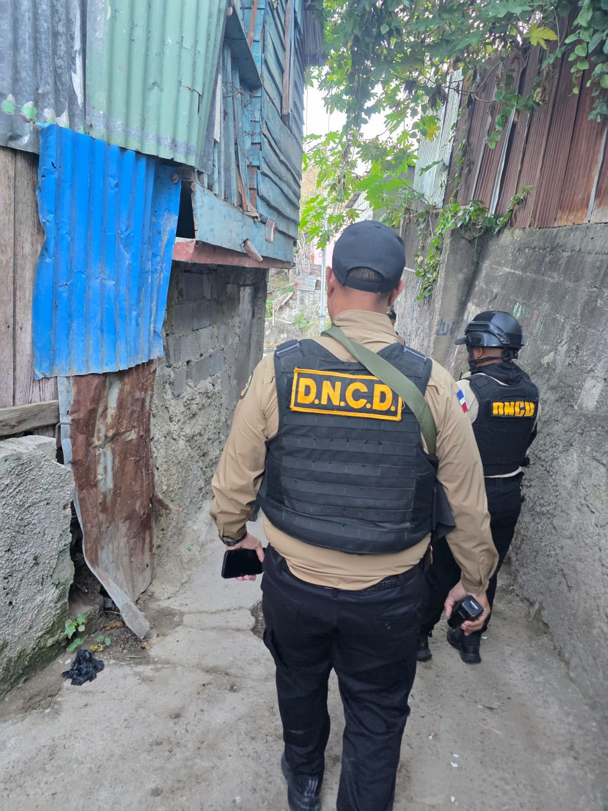 Agentes de la DNCD avanzan por un callejón durante operativo antidrogas y captura de prófugo en Constanza