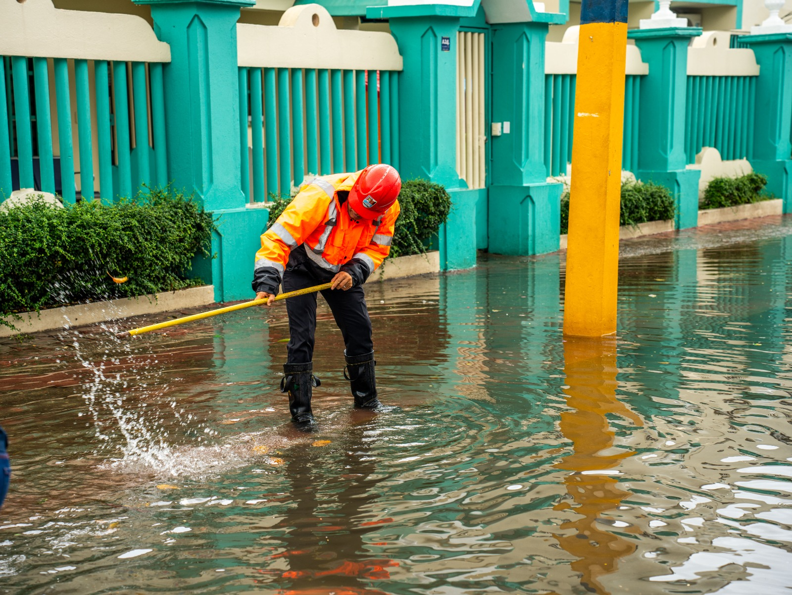Brigadista trabaja en calle inundada en Santo Domingo Este para destapar drenajes y evitar más inundaciones