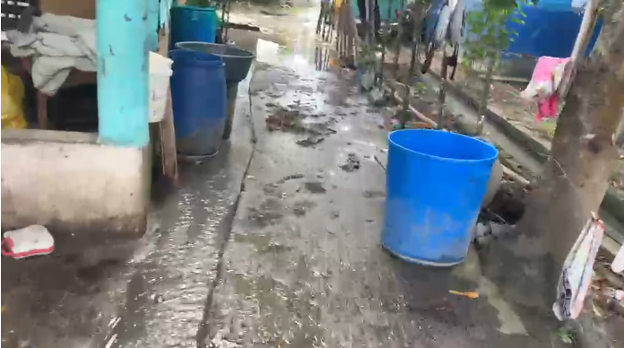 Agua de inundación corre por un callejón entre viviendas en La Ermita, Espaillat, debido al fuerte oleaje