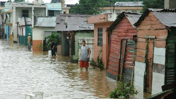Vecinos caminan entre viviendas inundadas en República Dominicana tras las lluvias que dejaron miles de desplazados