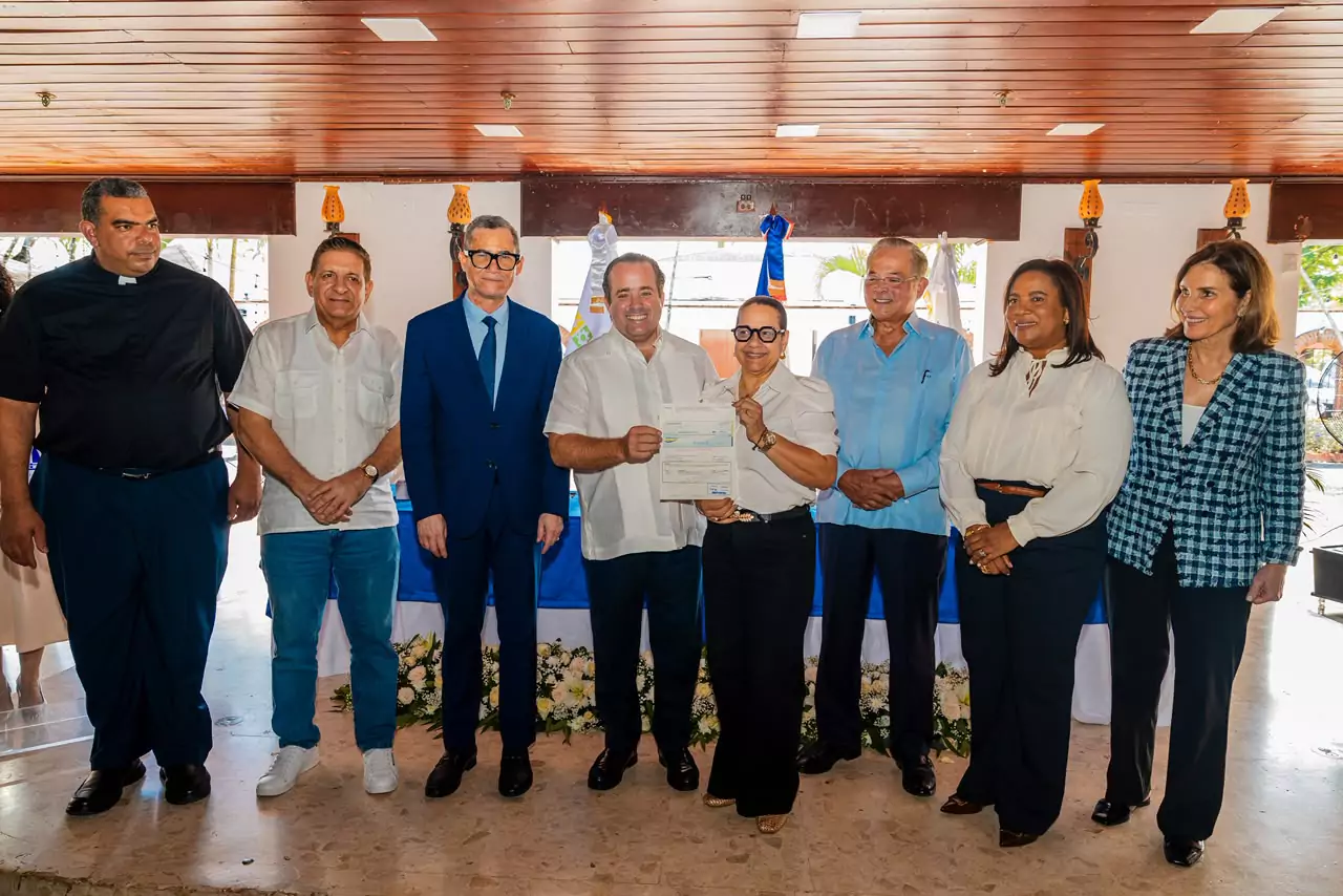 Funcionarios y beneficiario muestran documento durante entrega de pagos a desempleados y pensionados de Falconbridge en República Dominicana
