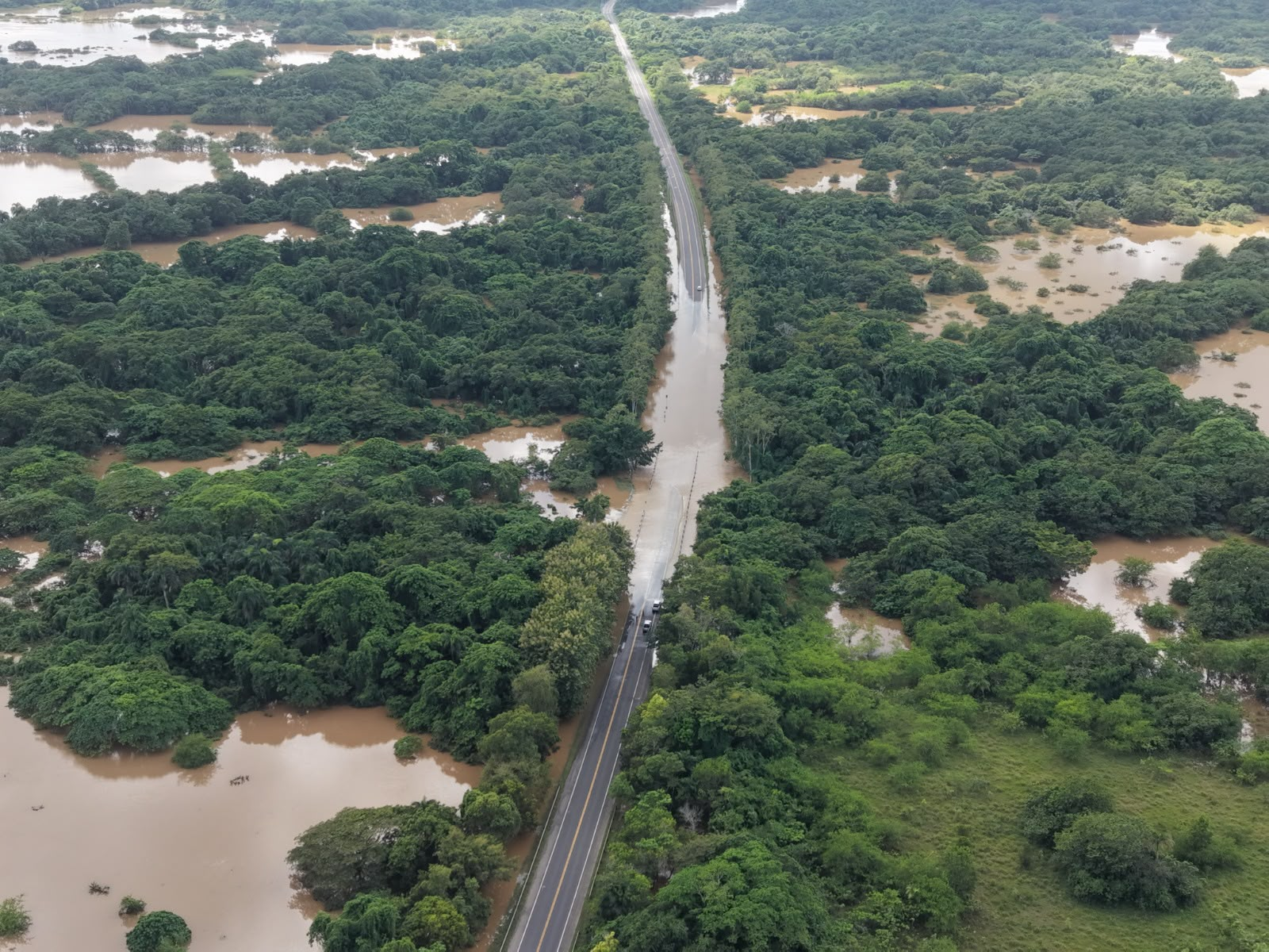 Vista aérea de la carretera Juan Pablo II inundada por inundaciones en Monte Plata, con tramos de la vía cubiertos por agua.