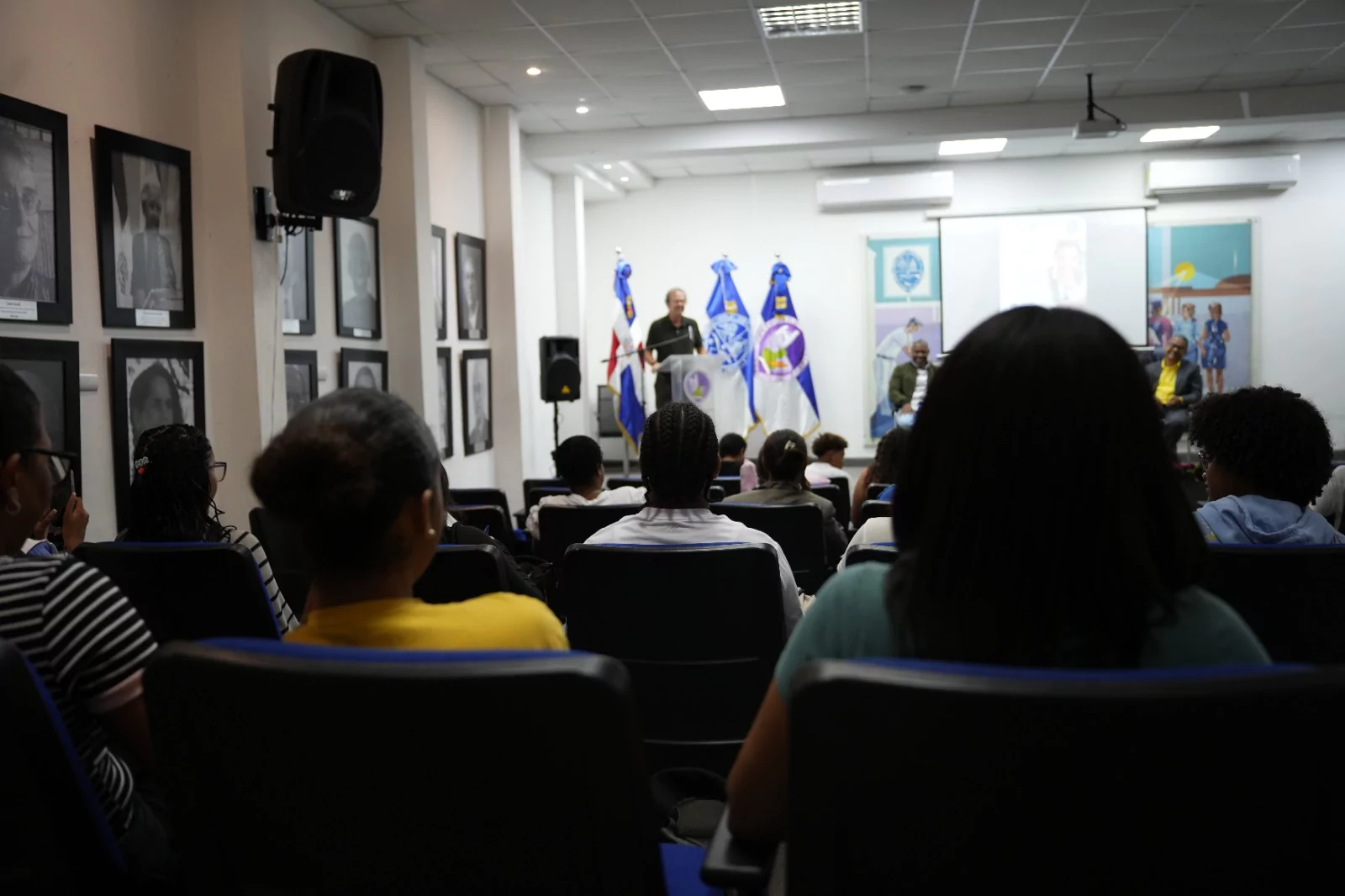 Asistentes escuchan charla en el salón de actos de la universidad durante actividad de Feria del Libro en instituciones académicas